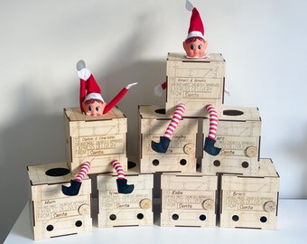 May include: Six wooden boxes with elf figures peeking out of the top. Each box has a personalised label with the text "TO [name] CHECKED NICE HEAD ELF APPROVED EXPRESS DELIVERY FROM SANTA".