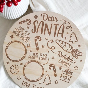 May include: A round wooden plate with a Christmas theme. It has a message that says "Dear Santa" and includes a place for a cookie, a carrot, and a drink. The plate is signed "Love, Ziggy".