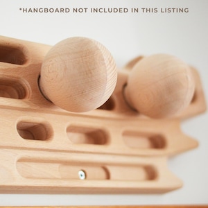 May include: Two light-colored wooden spheres attached to a wooden training board with various carved finger slots and pockets. The text *HANGBOARD NOT INCLUDED IN THIS LISTING is visible at the top of the image, indicating the board is separate.