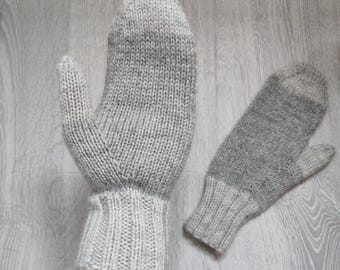 Puede incluir: Un par de mitones grises tejidos. Un mitón está en la mano de una persona, el otro está al lado. Los mitones tienen un puño acanalado y un patrón de tejido texturizado. El color es una mezcla de gris claro y medio.