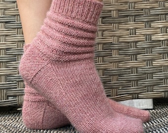 May include: A pair of pink knitted socks with a ribbed texture. The socks are folded down at the top, creating a cuff.