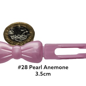 May include: Pink plastic hair clip with a bow shape. The clip is 3.5cm long and has a pearl-like finish. The text "#28 Pearl Anemone 3.5cm" is printed below the clip.