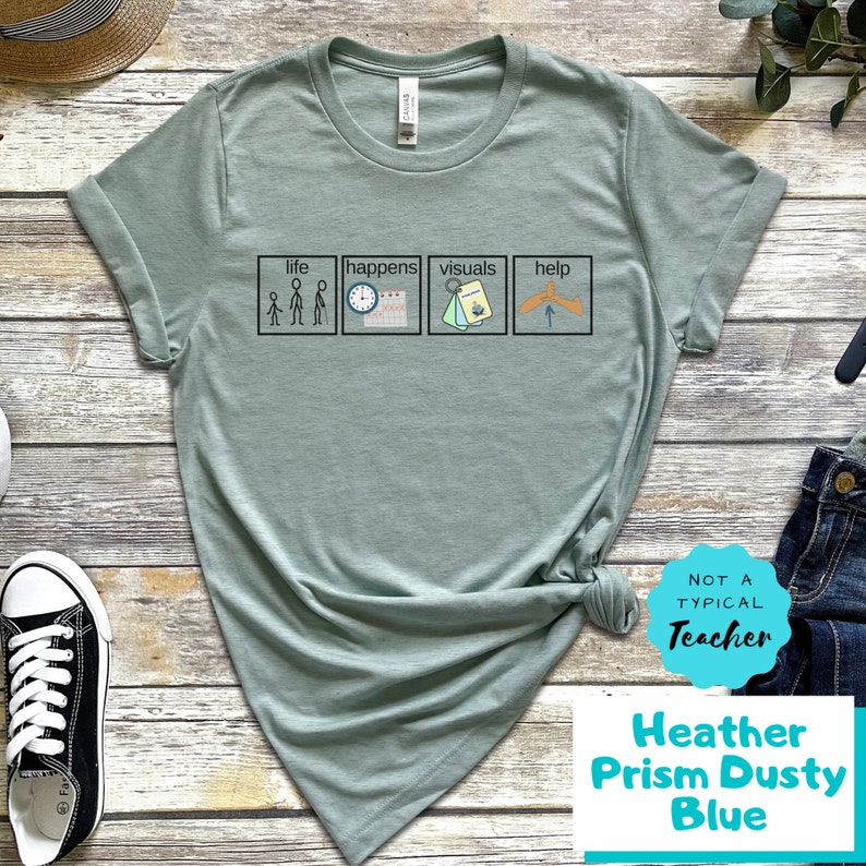 May include: A light green t-shirt with a graphic of four squares with the words "life", "happens", "visuals", and "help" and stick figure illustrations. The text "Not a Typical Teacher" is on a white circle with a blue border. The text "Heather Prism Dusty Blue" is below the circle.