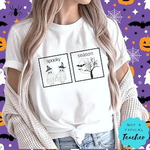K&ouml;nnte beinhalten: Wei&szlig;es T-Shirt mit einem Grafikdruck von zwei Geistern, die sich die H&auml;nde halten, vor einem Kasten mit der Aufschrift "spooky" und einem Baum mit Flederm&auml;usen vor einem Kasten mit der Aufschrift "season". Der Text "Not a Typical Teacher" befindet sich in einem blauen Kreis unten rechts im Bild.