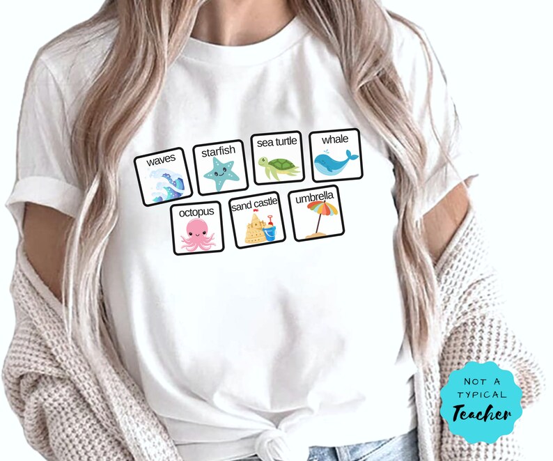 K&ouml;nnte beinhalten: Wei&szlig;es T-Shirt mit einer Grafik aus bunten Cartoon-Bildern von Meeresmotiven, darunter Wellen, Seesterne, Meeresschildkr&ouml;ten, Wale, Kraken, Sandburgen und Regenschirme. Der Text "NOT A TYPICAL TEACHER" ist unten rechts auf dem Shirt aufgedruckt.