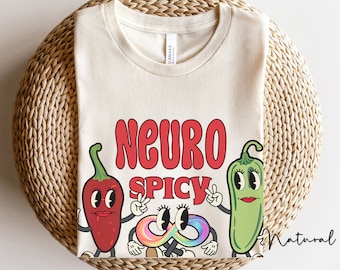 Könnte beinhalten: Cremefarbenes T-Shirt mit den Worten "NEURO SPICY" in roter Schrift im Retro-Stil. Das Shirt zeigt Cartoon-Chilischoten und ein farbenfrohes Unendlichkeitszeichen. Das Wort "Natural" ist in Kursivschrift unten rechts geschrieben.
