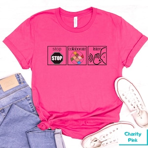May include: Pink t-shirt with a graphic design featuring three icons: a stop sign, a group of hands clasped together, and a hand over an ear. The text "stop", "collaborate", and "listen" are above each icon.