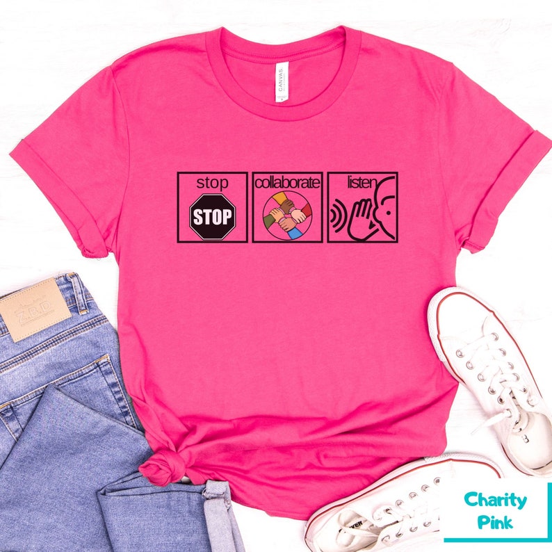May include: Pink t-shirt with a graphic design featuring three icons: a stop sign, a group of hands clasped together, and a hand over an ear. The text "stop", "collaborate", and "listen" are above each icon.