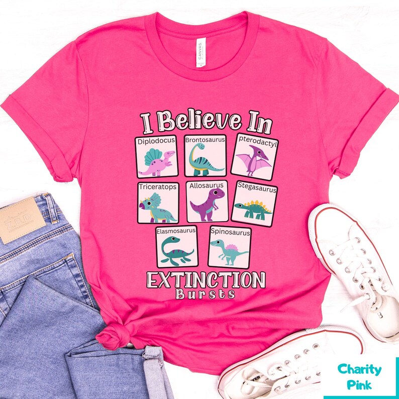 May include: Pink t-shirt with a graphic of dinosaurs and the text "I Believe In Extinction Bursts".