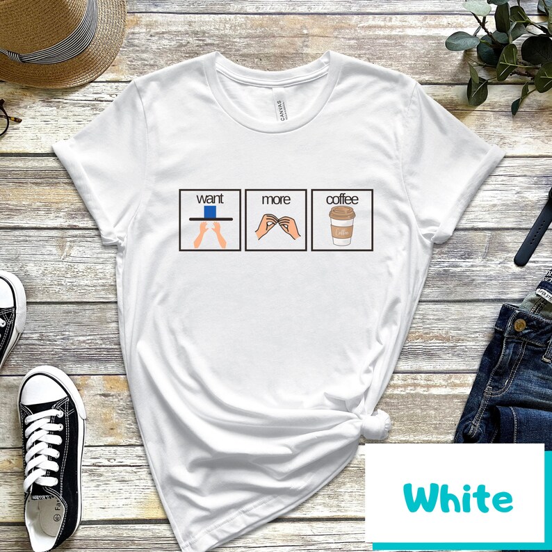 May include: White t-shirt with a graphic of three boxes. The first box says "want" and has a hand gesture for "want". The second box says "more" and has a hand gesture for "more". The third box says "coffee" and has a cartoon image of a cup of coffee.