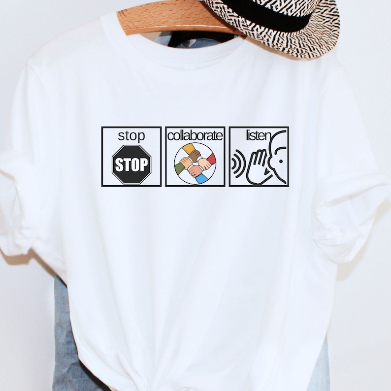 May include: White t-shirt with a graphic of three icons. The first icon is a red stop sign with the word "STOP" in white. The second icon is a circle with five hands of different skin tones clasped together. The third icon is a hand cupping an ear with the word "listen" above it.