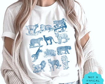 May include: White t-shirt with a blue print of various wild cats, including a lion, tiger, leopard, and lynx. The text "Not a Typical Teacher" is on a blue circle in the bottom right corner.