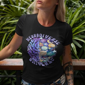 Może przedstawiać: Czarny T-shirt z fioletową i niebieską grafiką m&oacute;zgu z planetami i gwiazdami w środku. Tekst "Neurodiverse Universe" jest napisany wok&oacute;ł grafiki.