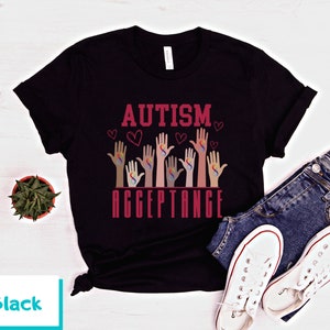 May include: Black t-shirt with the text "AUTISM ACCEPTANCE" in red lettering. The design features multiple hands with the autism awareness symbol in rainbow colors.