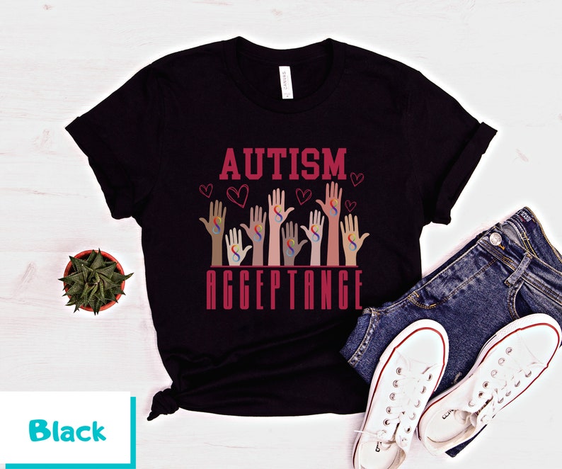 May include: Black t-shirt with the text "AUTISM ACCEPTANCE" in red lettering. The design features multiple hands with the autism awareness symbol in rainbow colors.