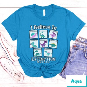 May include: A turquoise blue t-shirt with a graphic of dinosaurs and the text "I Believe In Extinction Bursts".