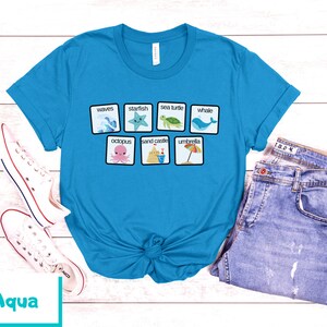 K&ouml;nnte beinhalten: Ein t&uuml;rkisfarbenes T-Shirt mit einer wei&szlig;en Grafik von Strandmotiven und W&ouml;rtern, darunter "Wellen", "Seestern", "Meeresschildkr&ouml;te", "Wal", "Kraken", "Sandburg" und "Sonnenschirm".