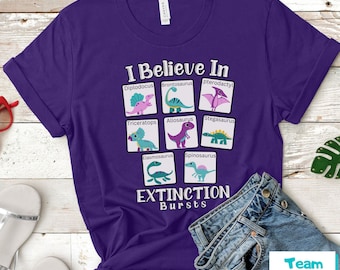 May include: Purple t-shirt with a graphic of dinosaurs and the text "I Believe In Extinction Bursts".