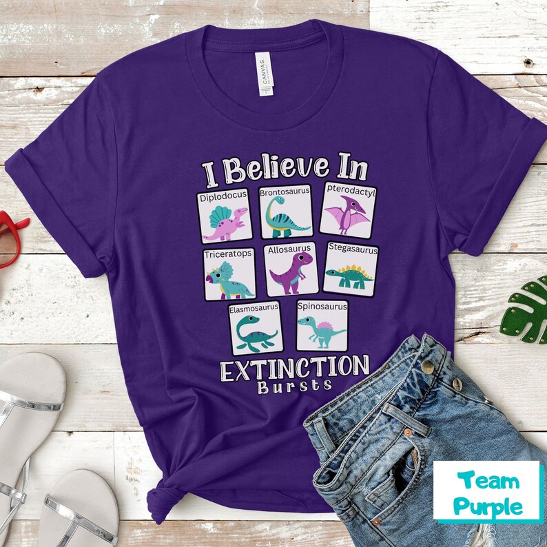 May include: Purple t-shirt with a graphic of dinosaurs and the text "I Believe In Extinction Bursts".