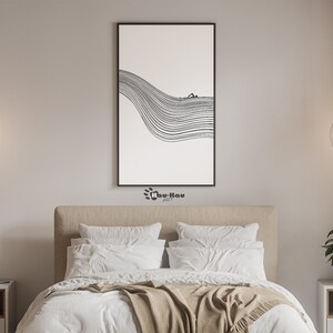 May include: A bedroom interior with a bed, two bedside tables, and two pendant lights. The bed has a beige headboard and white bedding. The bedside tables are white with a wooden top. The pendant lights are clear glass globes with gold accents. A black and white abstract line art print hangs above the bed.