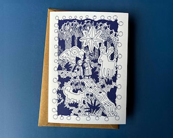 Puede incluir: Una tarjeta de felicitación con una ilustración azul y blanca de una escena invernal. La tarjeta presenta un búho, un ciervo, un zorro y figuras bajo una estrella. La tarjeta está dentro de un sobre marrón, sobre un fondo azul.