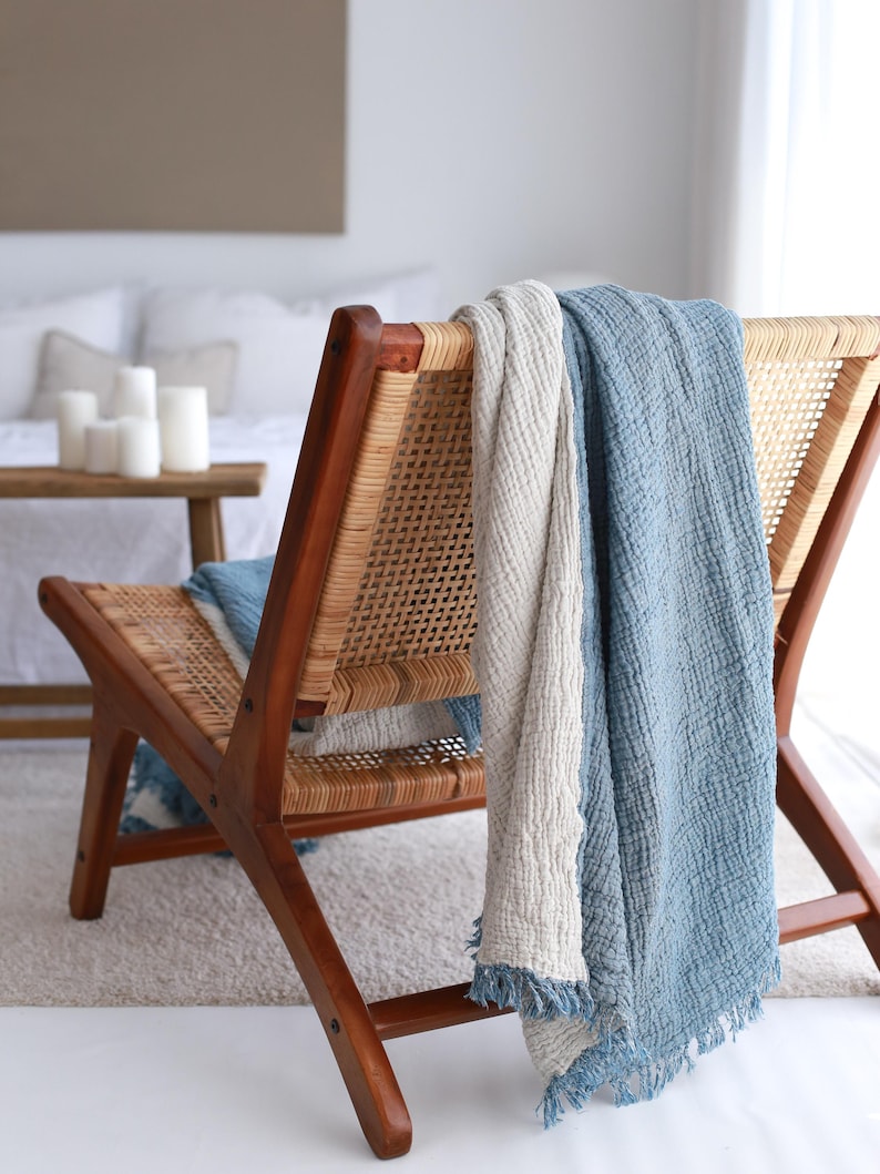 May include: A wooden chair with a woven cane seat and back. A blue and white throw blanket is draped over the back of the chair.
