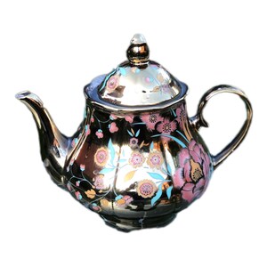 May include: A black ceramic teapot with a gold metallic finish and floral design. The teapot has a lid with a knob and a spout. The floral design features pink, blue, and gold accents.