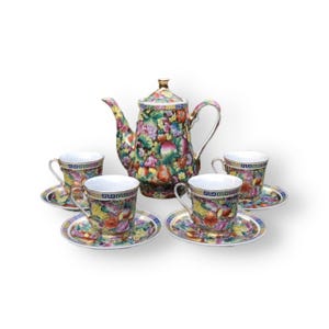 May include: A porcelain tea set with a floral pattern. The set includes a teapot and four cups and saucers. The teapot has a gold handle and spout. The cups and saucers have a floral pattern with gold accents.