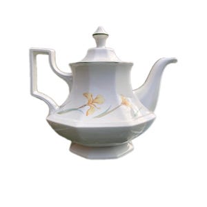 May include: White teapot with a green trim and yellow floral design. The teapot has an octagonal base and a lid with a finial.