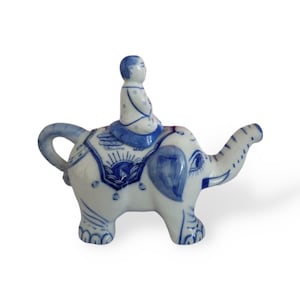 Peut inclure: Théière en porcelaine bleue et blanche en forme d'éléphant avec une petite figurine d'une personne assise sur son dos.