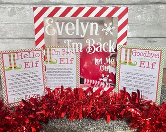 Puede incluir: Una caja de regalo navideña con diseño de rayas rojas y blancas, con el nombre "Evelyn" y un copo de nieve. Incluye tarjetas con mensajes de un elfo y un globo rojo.