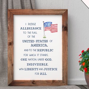 May include: A framed print with the Pledge of Allegiance to the United States of America. The print features a watercolor illustration of the American flag.