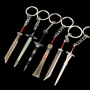 Könnte beinhalten: Sechs Miniatur-Schwert-Schlüsselanhänger mit silbernen Klingen, roten Akzenten und silbernen Schlüsselringen. Die Schwerter haben verschiedene Designs, darunter eine zweischneidige Klinge, eine gebogene Klinge und eine Klinge mit Parierstange. Die Schlüsselanhänger werden vor schwarzem Hintergrund präsentiert.