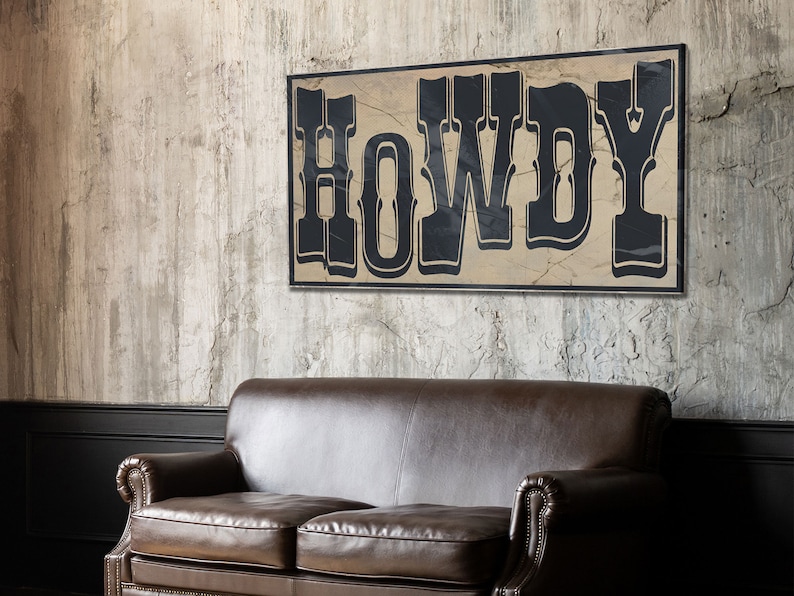 May include: A rustic wooden sign with the word "HOWDY" in black lettering on a beige background. The sign is hanging on a textured gray wall above a brown leather couch.