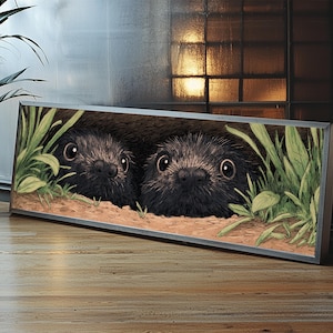 May include: A framed art print featuring two dark-furred creatures peeking out from a burrow. The artwork includes green foliage and a sandy ground, set against a neutral background. The print is displayed on a wooden surface.