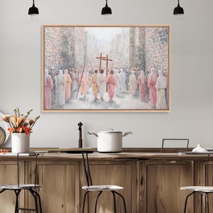 May include: A framed painting depicts a religious scene with figures in robes walking between stone walls. Two crosses are carried in the procession. The artwork is in soft pastel colors, with a focus on the central figures.