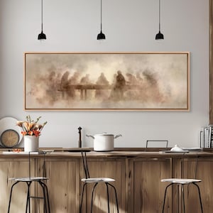 May include: A framed rectangular artwork depicting a sepia-toned scene of figures seated at a long table. The artwork is mounted on a light-colored wooden frame. The image is displayed above a wooden kitchen counter with stools.
