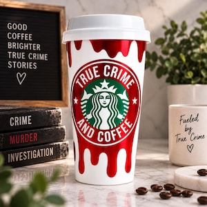 May include: A white reusable coffee cup with a white lid, featuring a red metallic drip design and a circular green and white logo with the text True Crime and Coffee. The cup is positioned in front of a letter board and stacked books.
