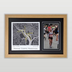 May include: A framed photo collage featuring a map of the Marine Corps Marathon route in Washington, D.C. and a photo of a runner crossing the finish line. The map is gray with a yellow route line. The runner is wearing a red running shirt with the number 4148 on it. The text "MARY THORNE 03:23:45 MARINE CORPS MARATHON" is printed below the map.