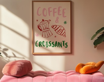 Könnte beinhalten: Ein gerahmter Druck mit den Worten "COFFEE & CROISSANTS" in Rosa und Grün, mit Illustrationen einer Kaffeekanne und eines Croissants. Darunter eine rosafarbene Samtbank mit einem rosafarbenen Kissen und einem orangefarbenen Kissen.