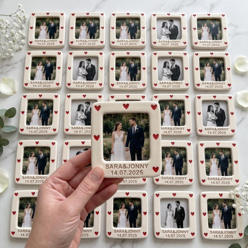 Pode incluir: Uma cole&ccedil;&atilde;o de molduras quadradas de cer&acirc;mica com acabamento branco e pequenos cora&ccedil;&otilde;es vermelhos impressos na borda. Cada moldura cont&eacute;m uma fotografia de um casal e &eacute; personalizada com o texto SARA & JONNY e a data 14.07.2025.