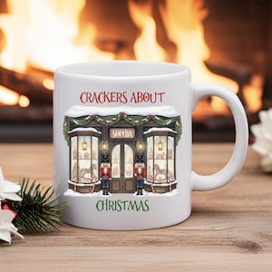 May include: White ceramic mug with a Christmas design. The mug features a shop illustration with nutcracker soldiers, the text "CRACKERS ABOUT CHRISTMAS", and the name "SOPHIA". A cozy fireplace is in the background.