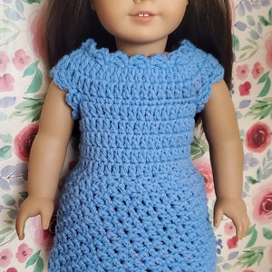 May include: A blue crocheted dress with a scalloped neckline and short sleeves. The dress is worn by a doll with brown hair and blue eyes.