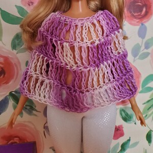 Puede incluir: Un poncho de ganchillo morado y blanco con una trama suelta y abierta.
