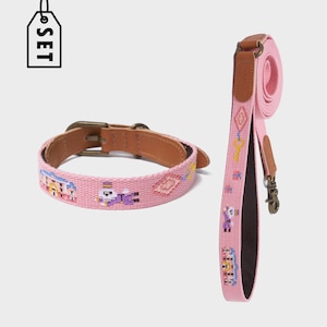 以下が含まれることがあります： ピンク色の犬用首輪とリードのセット。首輪とリードは、さまざまな色の刺繍されたピクセル化されたデザインのピンク色の生地で作られています。首輪は茶色の革の内側と真鍮のバックルが付いています。リードには真鍮製の留め金が付いています。