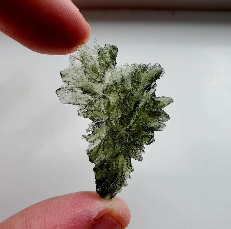 May include: A green, crystalline, moss agate specimen with a unique, branching, and textured shape.