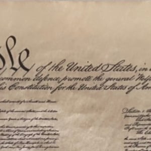 Könnte beinhalten: Ein Schwarzweißbild der ersten Seite der Verfassung der Vereinigten Staaten. Der Text lautet: "Wir, das Volk der Vereinigten Staaten, um eine vollkommenere Union zu bilden, Gerechtigkeit zu schaffen, die innere Ruhe zu gewährleisten, für die gemeinsame Verteidigung zu sorgen, das allgemeine Wohl zu fördern und die Segnungen der Freiheit für uns selbst und unsere Nachkommen zu sichern, verordnen und setzen diese Verfassung für die Vereinigten Staaten von Amerika fest."