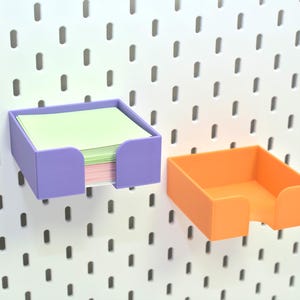 Könnte beinhalten: Zwei Wandorganizer, einer lila und einer orange, zum Aufbewahren von Haftnotizen oder anderen kleinen Gegenständen.