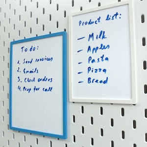 May include: Two white framed dry erase boards with blue trim. The left board has the text "To do:" and a list of four tasks. The right board has the text "Product list:" and a list of five items.
