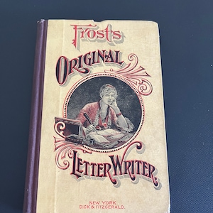 Op de afbeelding: Een vintage boek getiteld "Frost's Original Letter Writer" met een vrouw die aan een bureau schrijft in een cirkelvormige illustratie. De omslag is beige met rode en bruine letters en accenten. Het boek komt uit New York, uitgegeven door Dick & Fitzgerald.